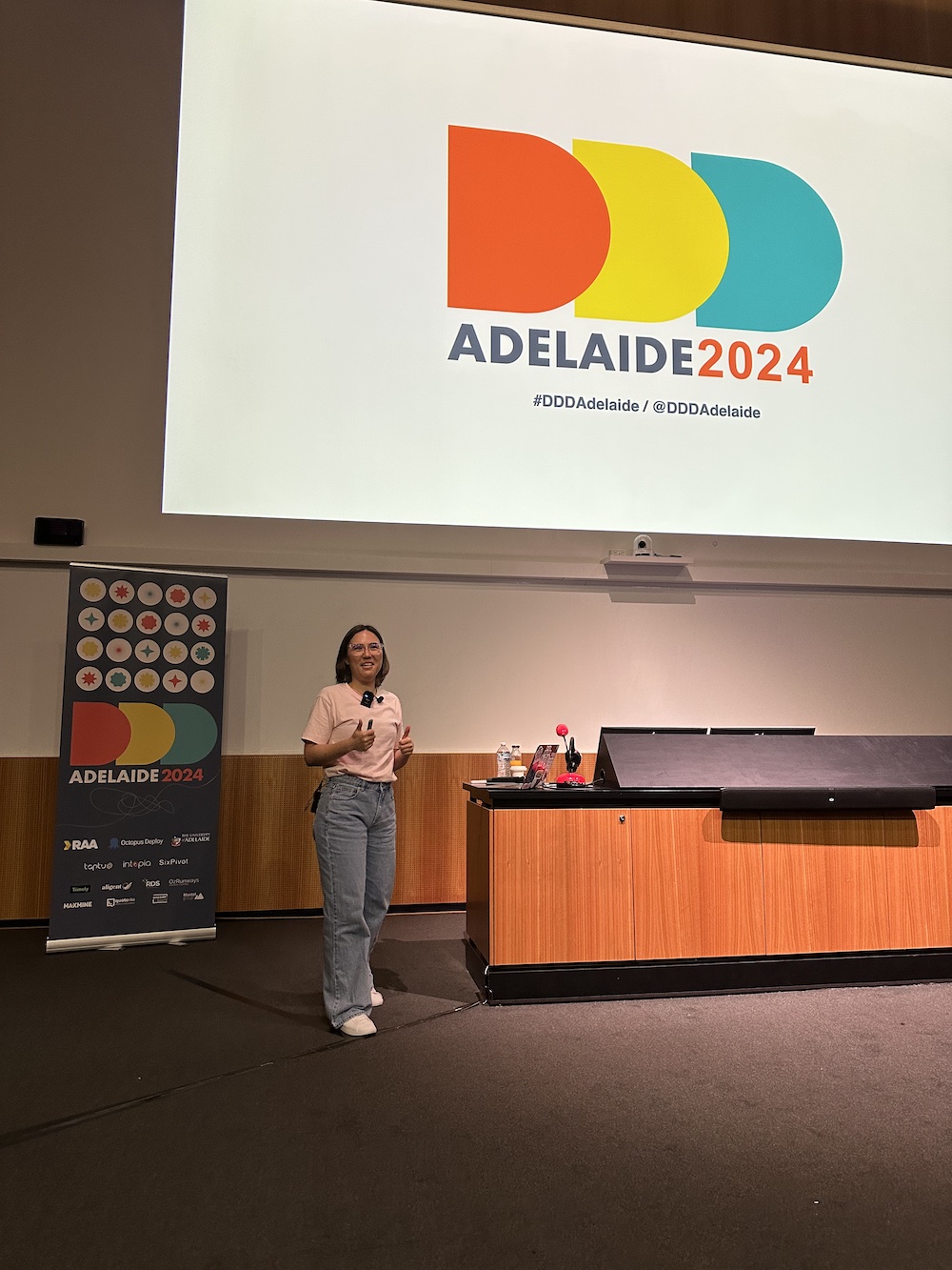 Larene standing on stage in front of a presentation slide for DDD Adelaide 2024.